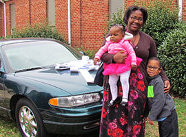 Aleesha with her two children standing in front of their car