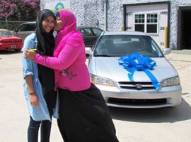Photo of Habibah hugging her daughter in front of their car